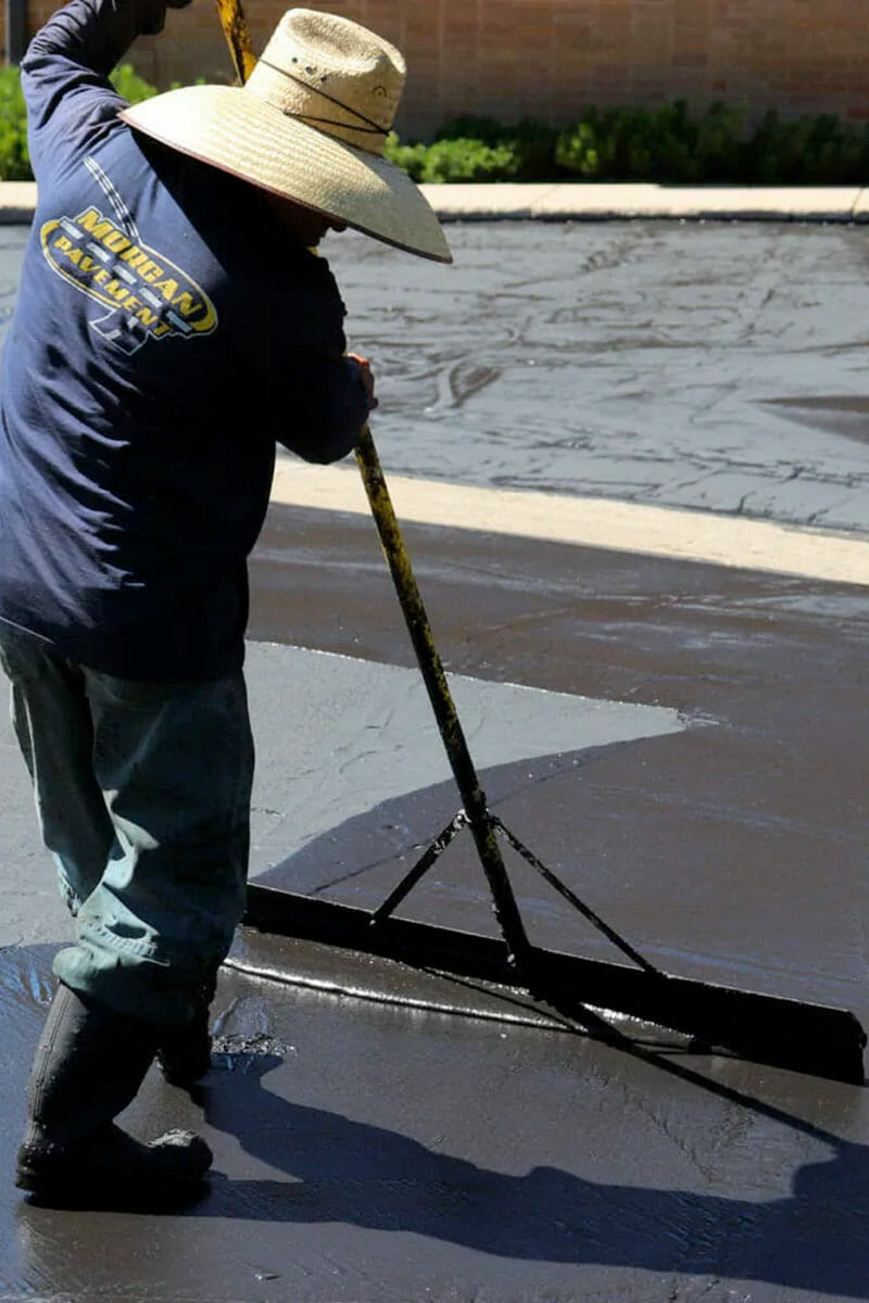 man smoothing out asphalt sealcoat